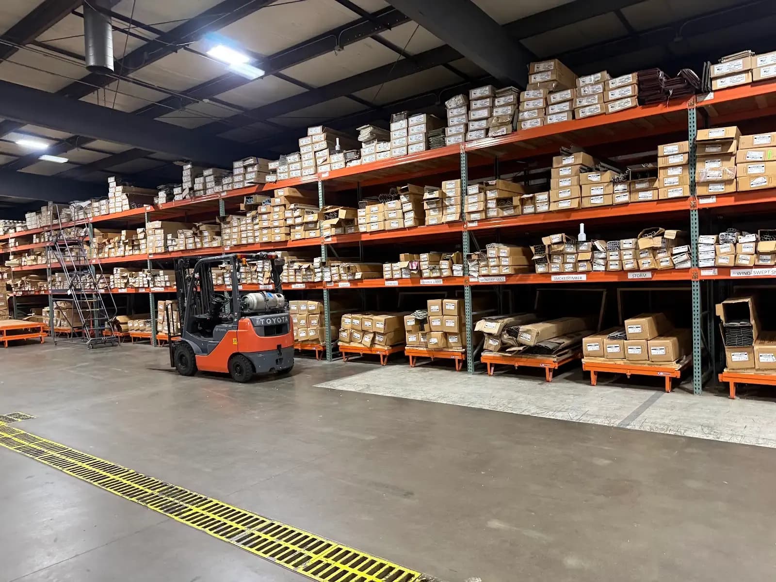 Pallet racking full of siding cartons and a forklift in the Suburban Wholesale warehouse